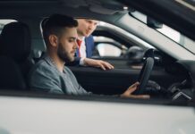 Mężczyzna ogląda wnętrze auta premium z pomocą sprzedawcy w salonie