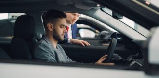Jak bezpiecznie kupić używane auto premium z importu: formalności, ryzyka i realne koszty Mężczyzna ogląda wnętrze auta premium z pomocą sprzedawcy w salonie