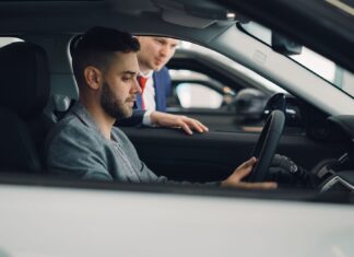 Mężczyzna ogląda wnętrze auta premium z pomocą sprzedawcy w salonie