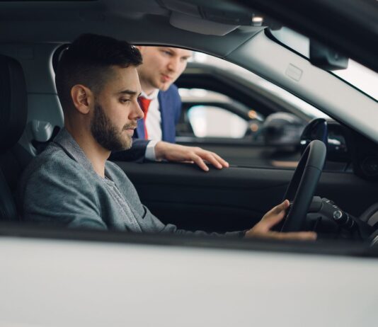 Jak bezpiecznie kupić używane auto premium z importu: formalności, ryzyka i realne koszty Mężczyzna ogląda wnętrze auta premium z pomocą sprzedawcy w salonie