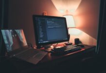 Ciepło oświetlone domowe biuro z dwoma monitorami do programowania