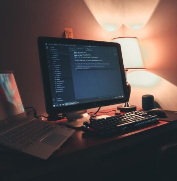 Ciepło oświetlone domowe biuro z dwoma monitorami do programowania