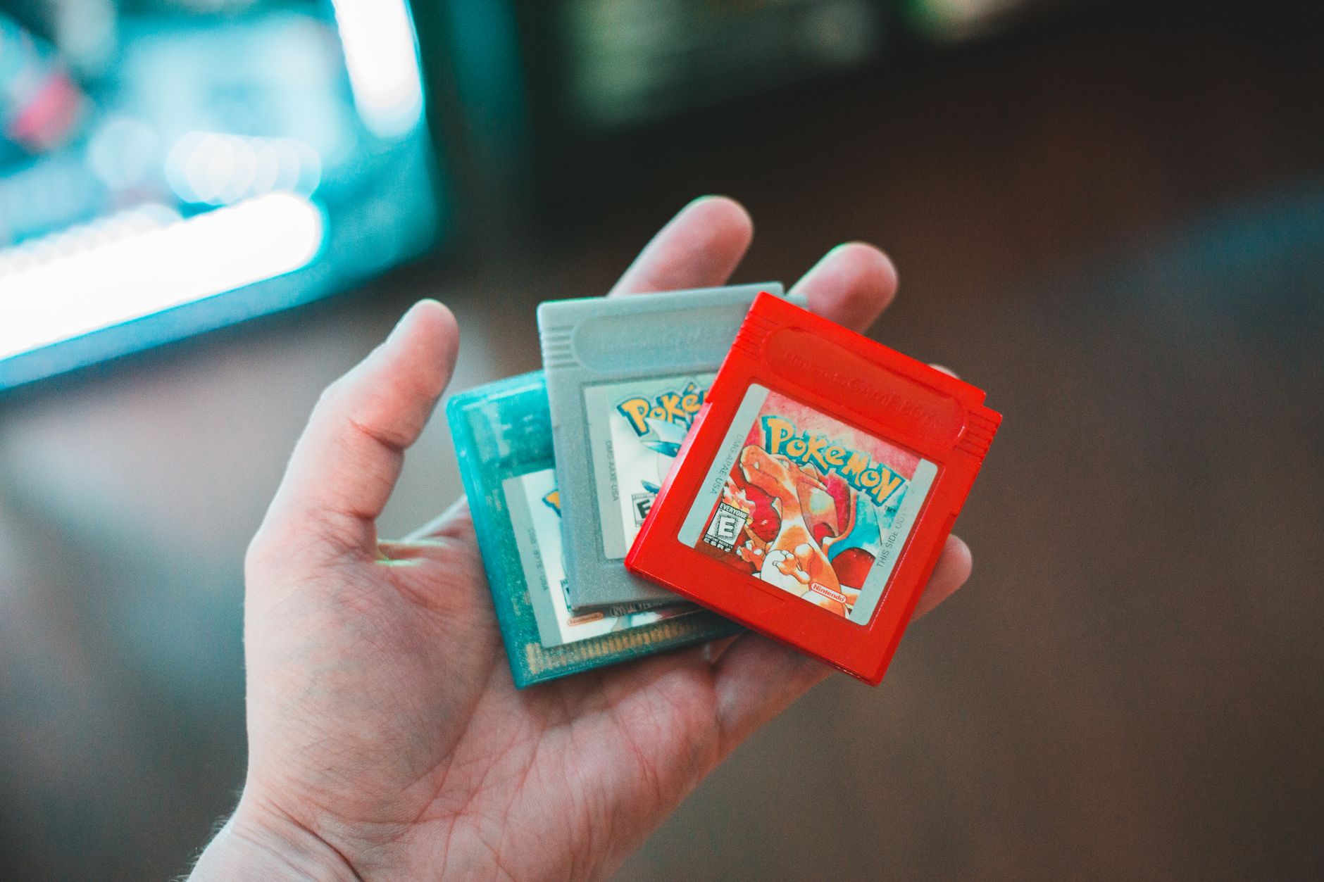 Dłoń trzymająca kartridże Pokemon, nostalgiczne gry retro