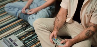Jak remastery starych gier uczą nowe pokolenie graczy szacunku do klasyki Dwoje dorosłych gra na retro konsoli siedząc na pasiastym dywanie