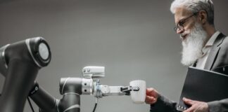 Jak sztuczna inteligencja zmienia rynek pracy w Polsce: kluczowe trendy i prognozy Starszy mężczyzna odbiera kubek od ramienia robota w nowoczesnym biurze
