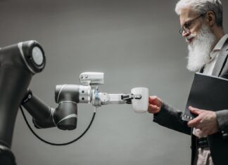 Starszy mężczyzna odbiera kubek od ramienia robota w nowoczesnym biurze