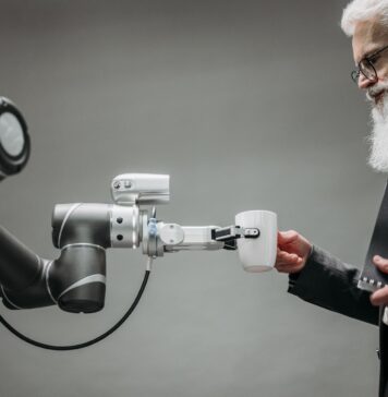 Starszy mężczyzna odbiera kubek od ramienia robota w nowoczesnym biurze
