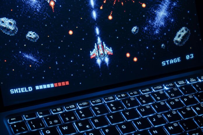 Laptop z retro kosmiczną strzelanką, podświetlana klawiatura
