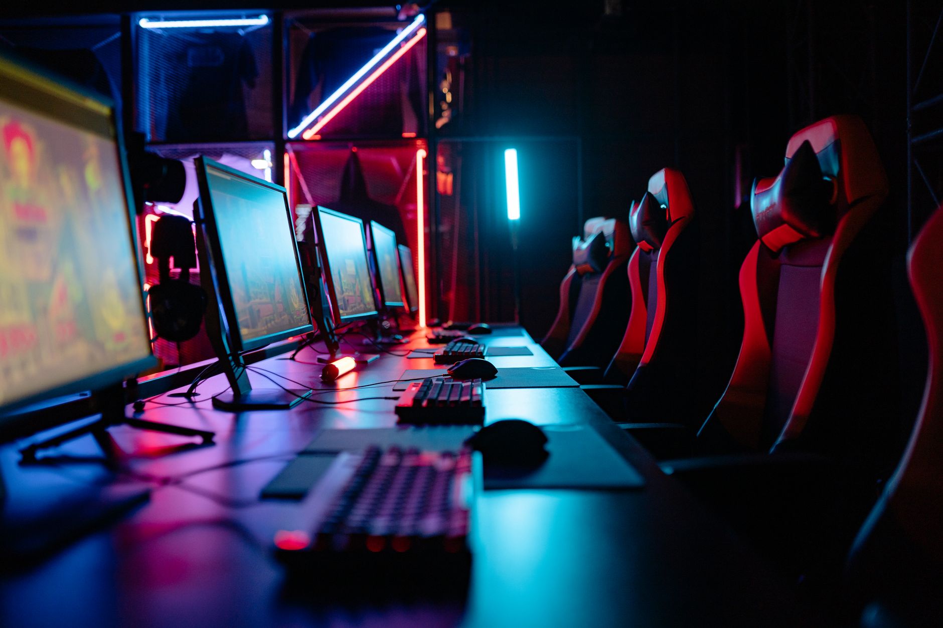 Neonowy pokój gamingowy z komputerami i fotelami turniejowymi