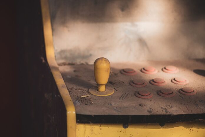 Zakurzony panel sterowania starego automatu arcade z joystickiem i przyciskami